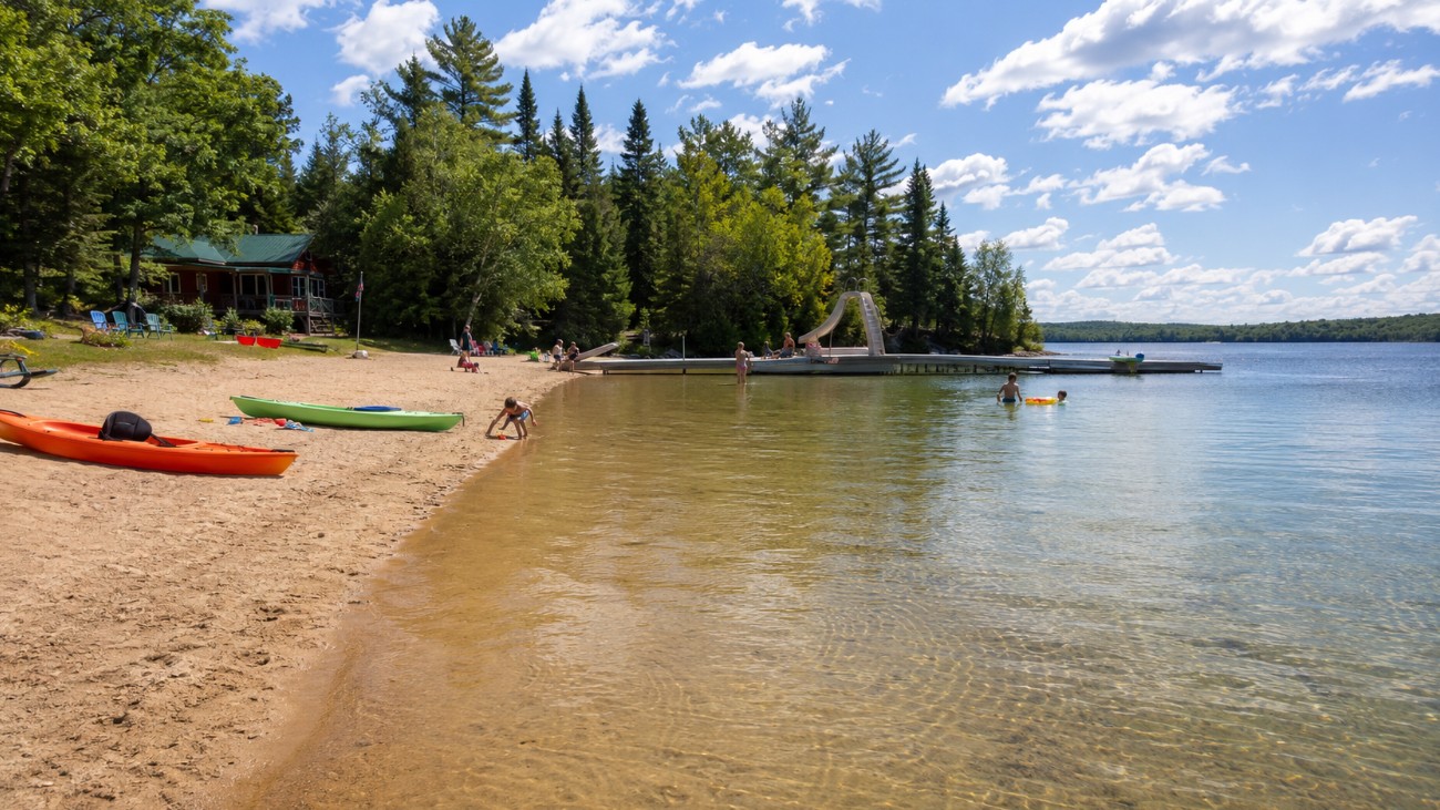 Sandy lakeside beach at a family fishing resort with kids playing near the water